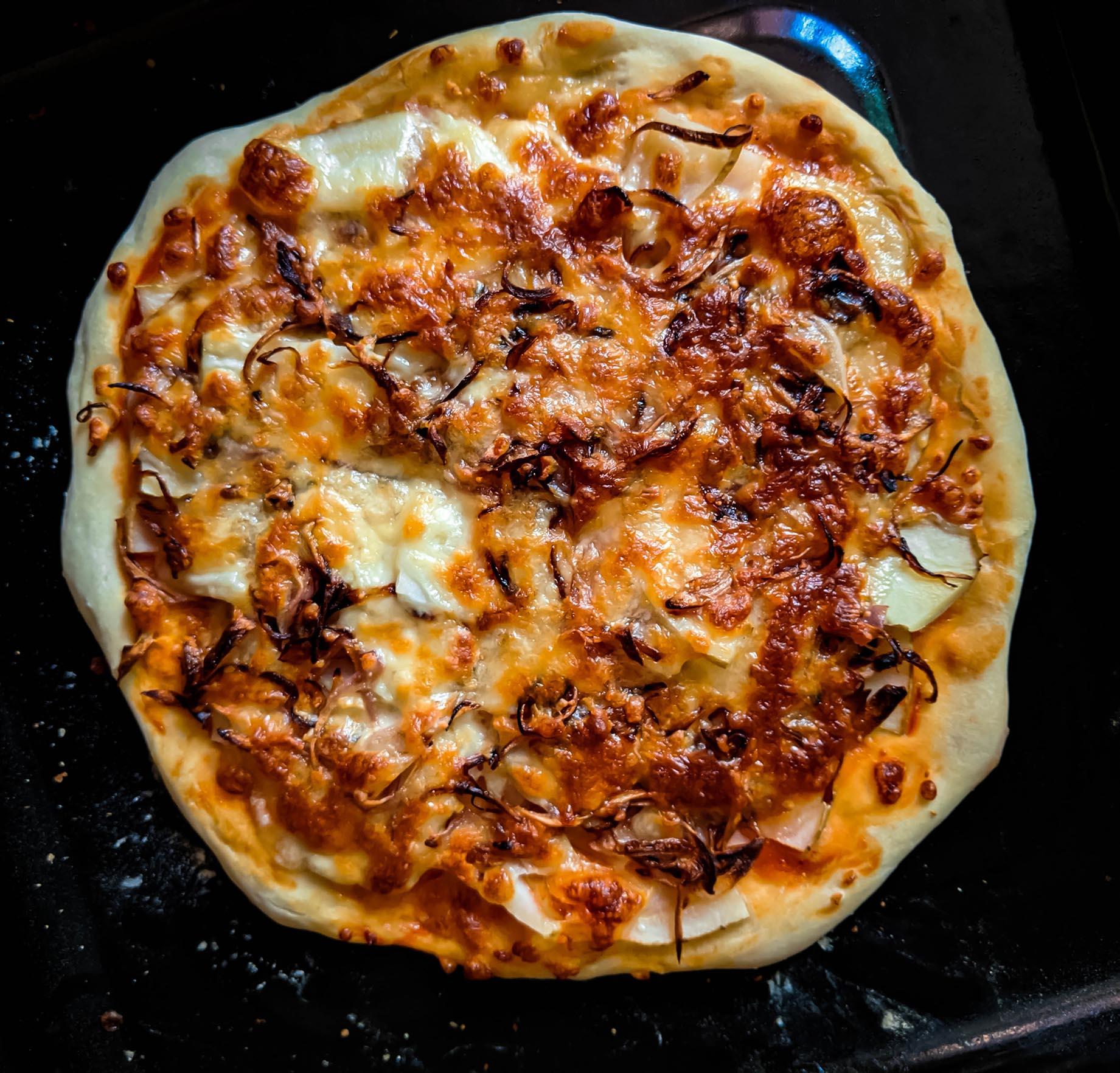 pizza topped with sliced potatoes and caramelized onions